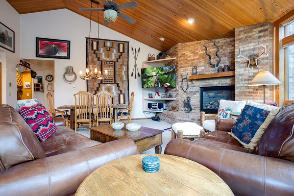 Sink into plush leather sofas in a striking vaulted living room where rustic charm meets modern comfort. Rich wood ceilings, exposed brick, and a glowing fireplace create your perfect retreat.