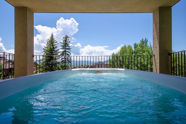 Sink into warm, bubbling waters while drinking in sweeping mountain views. This covered terrace hot tub invites you to unwind beneath open skies and evergreens.