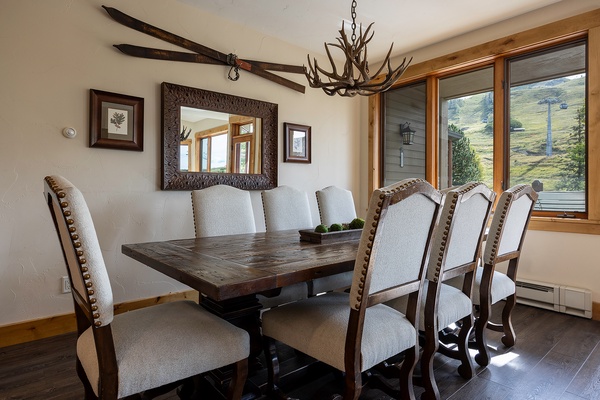 Gather around this handsome dining table where rustic mountain charm meets modern comfort, with natural light and scenic slopes framing your meals together.