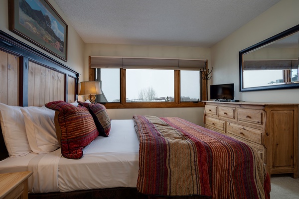 Sink into crisp white linens and colorful throws after a day of mountain adventures. Your cozy bedroom offers scenic views and rustic wood furnishings that feel like a home away from home.