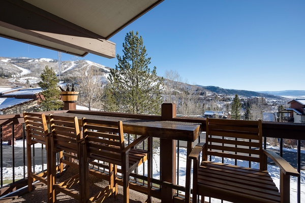 Expansive mountain views frame the covered terrace with outdoor seating, overlooking snow-dusted peaks and the valley below—perfect for morning coffee or evening relaxation.