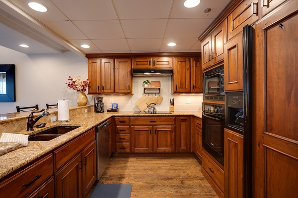 Step into your fully-equipped kitchen featuring rich wood cabinetry, granite countertops, and modern appliances—perfect for preparing family meals during your stay.