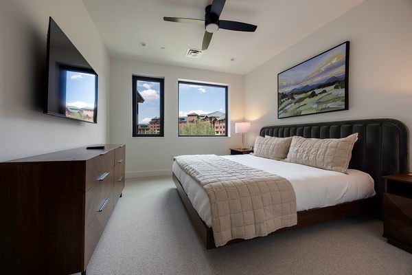Unwind in your bright, modern bedroom where mountains and sky frame your mornings. The plush bed and ceiling fan promise restful nights after exploring nearby attractions.