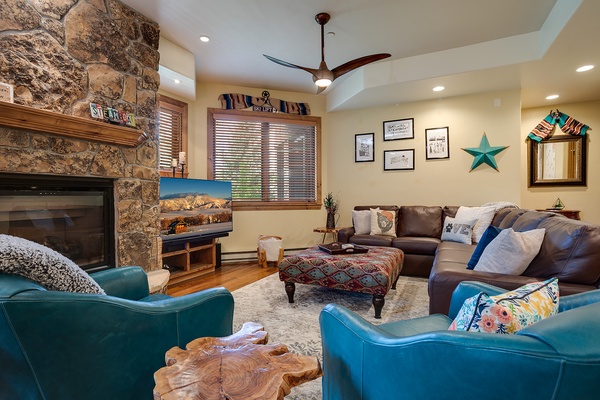 Unwind in your mountain-inspired living room with a cozy stone fireplace, plush seating, and vibrant pops of turquoise, where comfort meets charming Southwestern style.