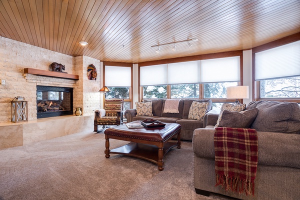 Sink into plush sofas by the crackling fireplace, where warm wood tones and mountain views create your perfect retreat after a day of adventure.