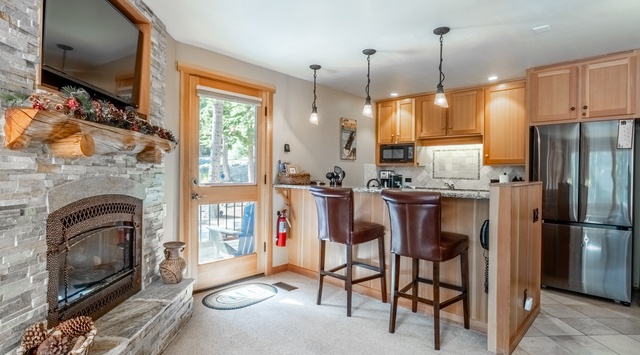 Your well-appointed kitchen welcomes you with warm wood cabinetry, stainless appliances, and a cozy stone fireplace—perfect for gathering over morning coffee or après-ski relaxation.