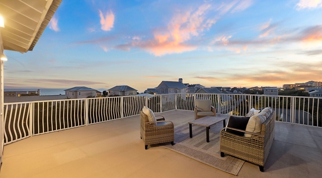 Unwind on your private rooftop terrace as golden sunset colors paint the sky above coastal homes.