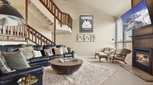 Sink into plush leather seating by your crackling fireplace, where mountain views and cozy textures create your perfect retreat.