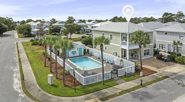Aerial view of coastal vacation homes featuring private pool, tropical landscaping, and convenient neighborhood location.