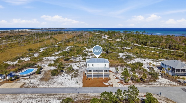 Coastal vacation home nestled among natural dunes and scattered palms, just steps from the beach.