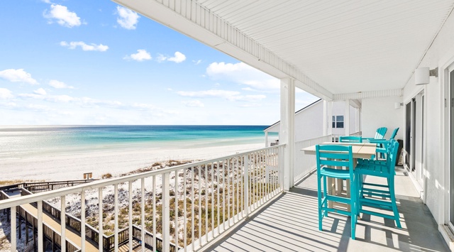 Your private oceanfront balcony offers stunning beach views with turquoise dining chairs perfect for morning coffee or sunset cocktails.