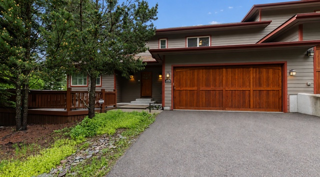 This modern vacation home features warm wood accents, convenient garage parking, and a private deck—all nestled among towering trees for a peaceful mountain retreat.