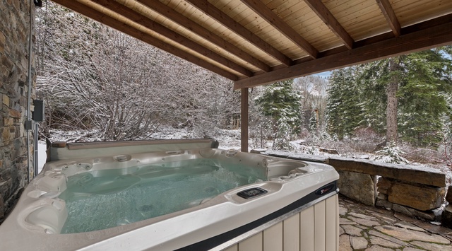 Soak in your private hot tub under rustic beams, watching snow blanket the peaceful forest—pure mountain bliss awaits.