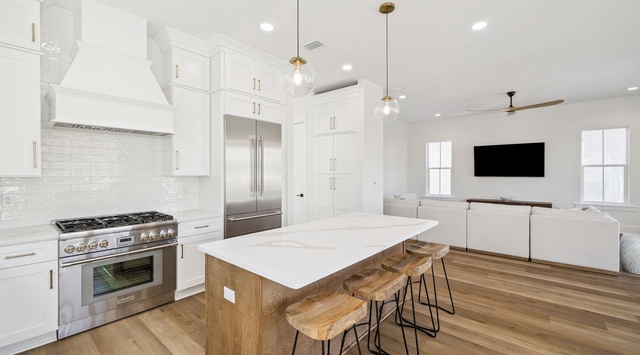 Your chef-worthy kitchen awaits with granite counters, gas range, and island seating flowing into the cozy living space.