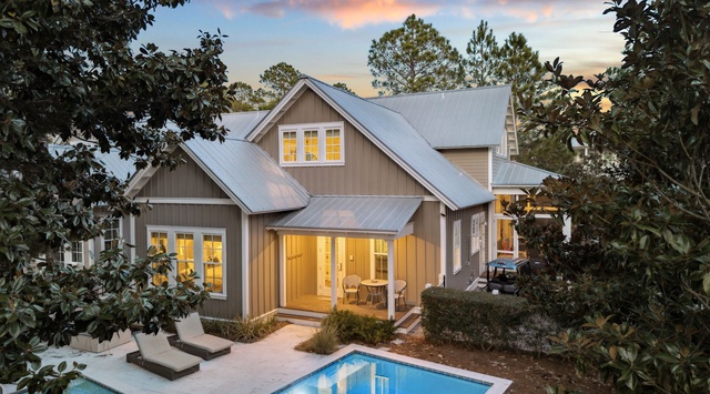 Stunning coastal cottage with private pool surrounded by lush landscaping, featuring warm evening lighting and peaceful outdoor retreat spaces.