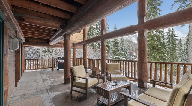 Unwind on your private covered terrace with plush seating, where rustic wood beams frame snowy mountain views—your perfect alpine retreat awaits.