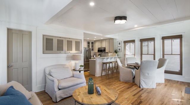 Relax in your open-concept living space, where coastal elegance meets comfort. Warm hardwood floors, shiplap ceilings, and soft natural light create a serene retreat perfect for unwinding after a day at the beach.