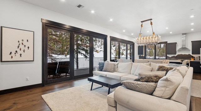 Sink into plush seating beneath a sparkling chandelier while winter views frame your cozy retreat through floor-to-ceiling windows.