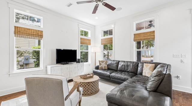 Relax on plush leather seating in your bright, airy living room, where ceiling fans keep you comfortable and large windows frame peaceful glimpses of the outdoors.