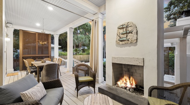 Gather around the glowing fireplace on your private patio, where coastal charm meets cozy comfort beneath soaring ceilings and tropical views.