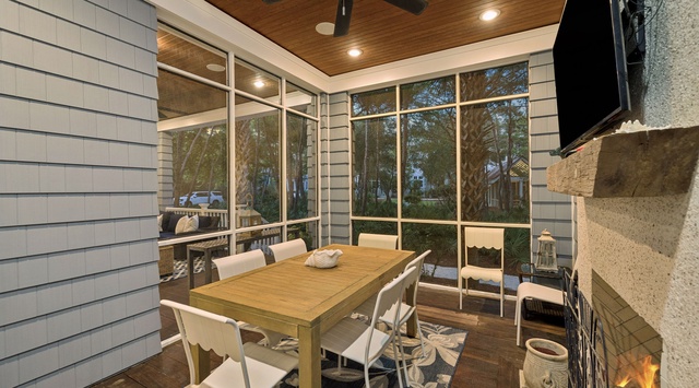 Gather around the table in your screened porch, where the ceiling fan keeps you cool while the fireplace adds warmth. Floor-to-ceiling windows frame peaceful views, creating your perfect indoor-outdoor retreat.