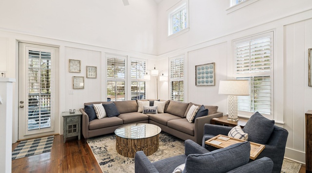 Relax in this sun-drenched living room where coastal elegance meets modern comfort, featuring soaring ceilings and abundant natural light.