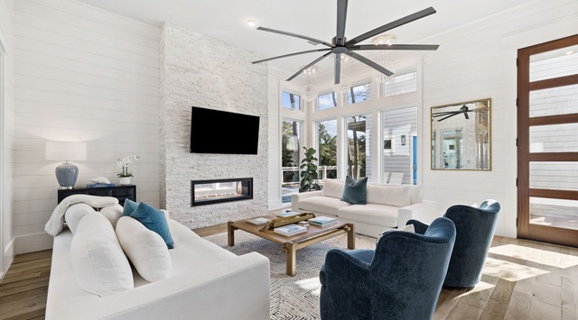 Sink into plush white sofas and navy armchairs in your elegant living space, where modern luxury meets comfort beneath soaring ceilings.
