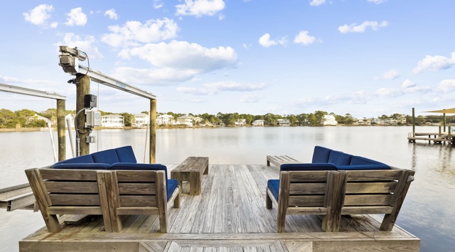 Waterfront seating with blue cushions offers peaceful lake views and distant neighborhood scenery from this lakeside dock.