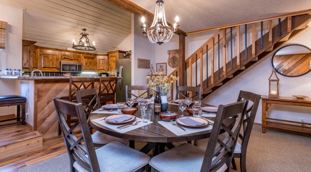 Gather around a beautifully set dining table beneath elegant chandeliers. This cozy open-concept space blends warm wood tones, rustic charm, and modern comforts—perfect for memorable meals and laughter with loved ones.