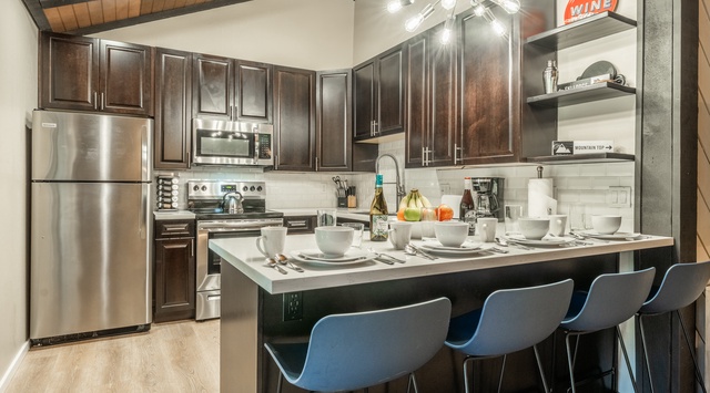 Your fully equipped kitchen invites you to cook and gather with sleek stainless appliances, rich wood cabinetry, and a breakfast bar perfect for morning coffee or casual meals together.