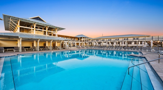 This stunning shared pool offers a refreshing oasis during golden hour. Modern two-story building with covered pavilion creates the perfect backdrop for relaxing poolside evenings.