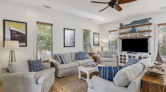 Relax in your coastal-inspired living room with plush seating, nautical decor, and entertainment center for perfect vacation evenings.