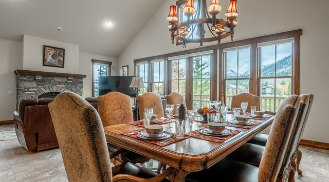 Gather around the elegant dining table where mountain views frame every meal, while the cozy fireplace and vaulted ceilings create a warm, inviting atmosphere for your memorable evenings together.