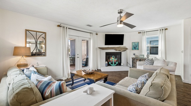Settle into this inviting living room where plush seating and coastal charm create your perfect gathering spot. The fireplace and ceiling fan keep you comfortable year-round.
