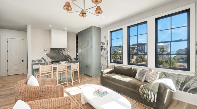 Sink into the plush sofa and soak in ocean views through floor-to-ceiling windows in this bright, coastal-inspired space.