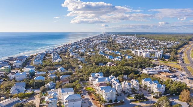 Coastal community nestled between pristine beaches and lush greenery, offering a peaceful seaside retreat setting.