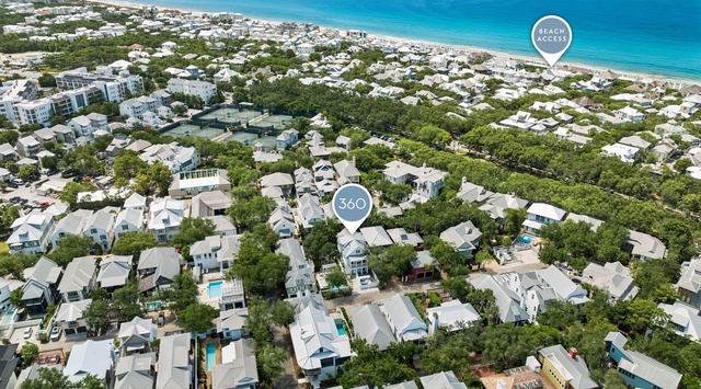 Aerial view of a coastal vacation neighborhood nestled among lush greenery, with the stunning turquoise ocean and pristine beach just a short walk away from the property.