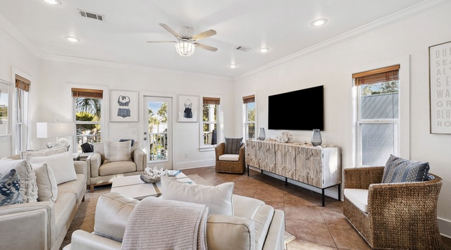 Unwind in your spacious living room with plush seating, coastal textures, and natural light streaming through bamboo shades.