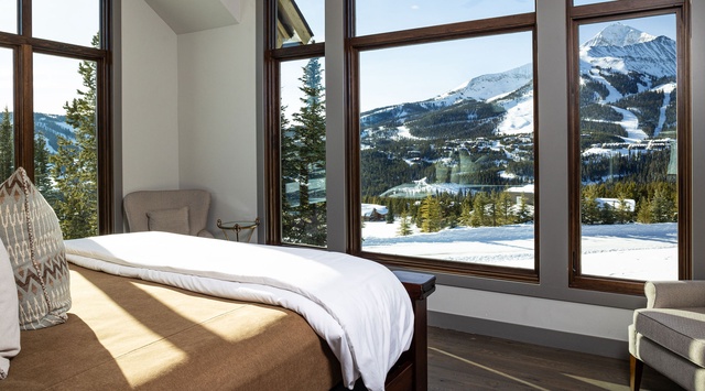 Wake up to a spectacular mountain vista framing your restful retreat, where floor-to-ceiling windows invite alpine serenity right into your cozy bedroom.