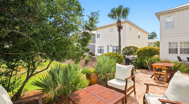 This property features a lush landscaped garden with tropical palms, mature trees, and well-maintained grounds surrounding modern two-story residential buildings photographed under clear daytime skies.