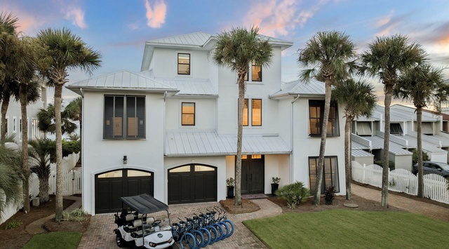 Coastal-inspired vacation home nestled among palm trees with convenient bicycles and golf cart ready for exploring the surrounding neighborhood.