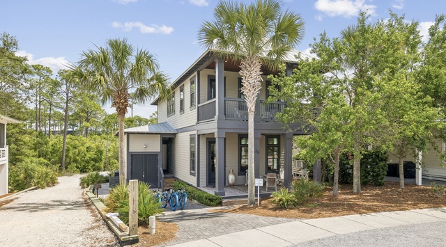 Modern coastal home nestled among native palms and oak trees in a peaceful residential setting, offering a welcoming arrival experience.