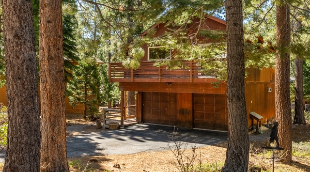 Nestled among towering pines, this mountain cabin features warm wood tones, a spacious upper deck, and convenient two-car parking—your perfect forest retreat awaits.