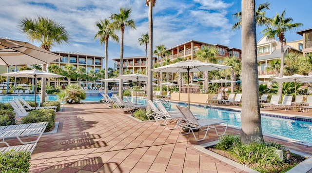 Resort features swimming pools surrounded by palm trees and modern accommodations in a tropical setting.