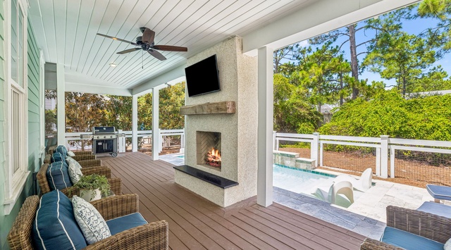 Step out onto your covered porch and unwind in plush wicker seating by the outdoor fireplace, with the pool and peaceful wooded surroundings just beyond.