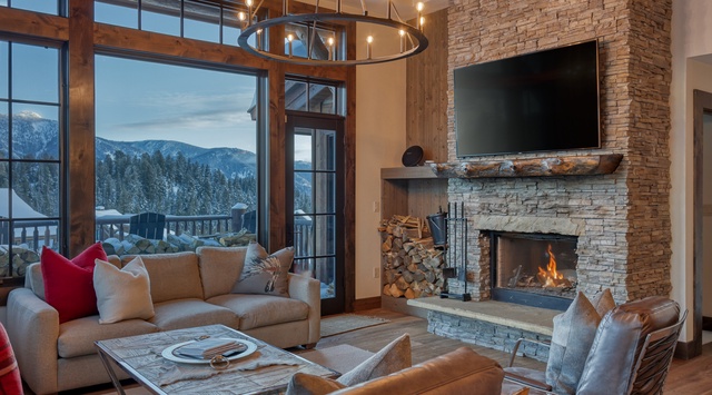 Sink into plush seating by the crackling fireplace while mountain views frame your perfect alpine retreat through floor-to-ceiling windows.