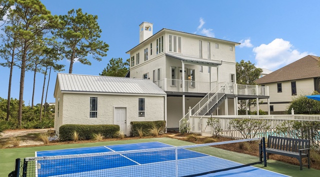 This coastal vacation home features a private tennis court nestled among mature pine trees. The elevated architecture and wraparound balconies provide the perfect retreat for active travelers and outdoor enthusiasts.