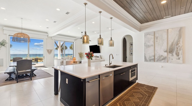 Your gourmet kitchen flows seamlessly into the living area, where stunning ocean views through floor-to-ceiling windows create the perfect backdrop for cooking and entertaining.