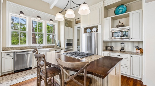 Your fully equipped gourmet kitchen features granite counters, stainless appliances, a gas range island, and bright windows overlooking tranquil wooded views—perfect for cooking and gathering.