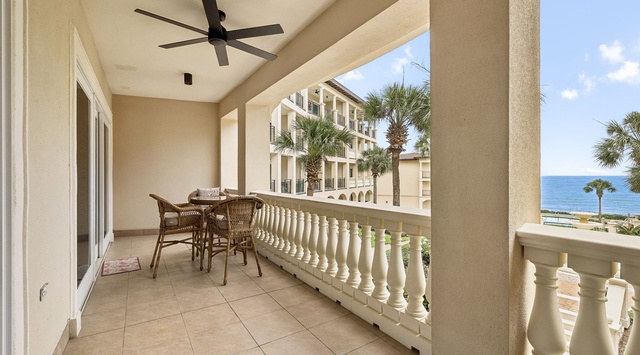 Your private balcony offers a peaceful retreat with wicker seating, gentle ceiling fan breezes, and stunning ocean views framed by swaying palms—perfect for morning coffee or sunset evenings.